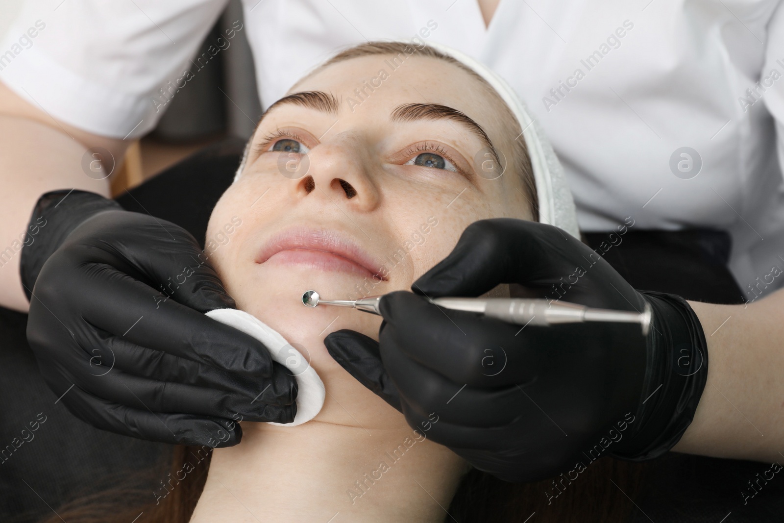 Photo of Cosmetologist using scrubber, closeup. Client having cleansing procedure