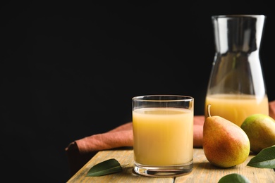 Photo of Fresh pear juice in glass and fruits on wooden table. Space for text