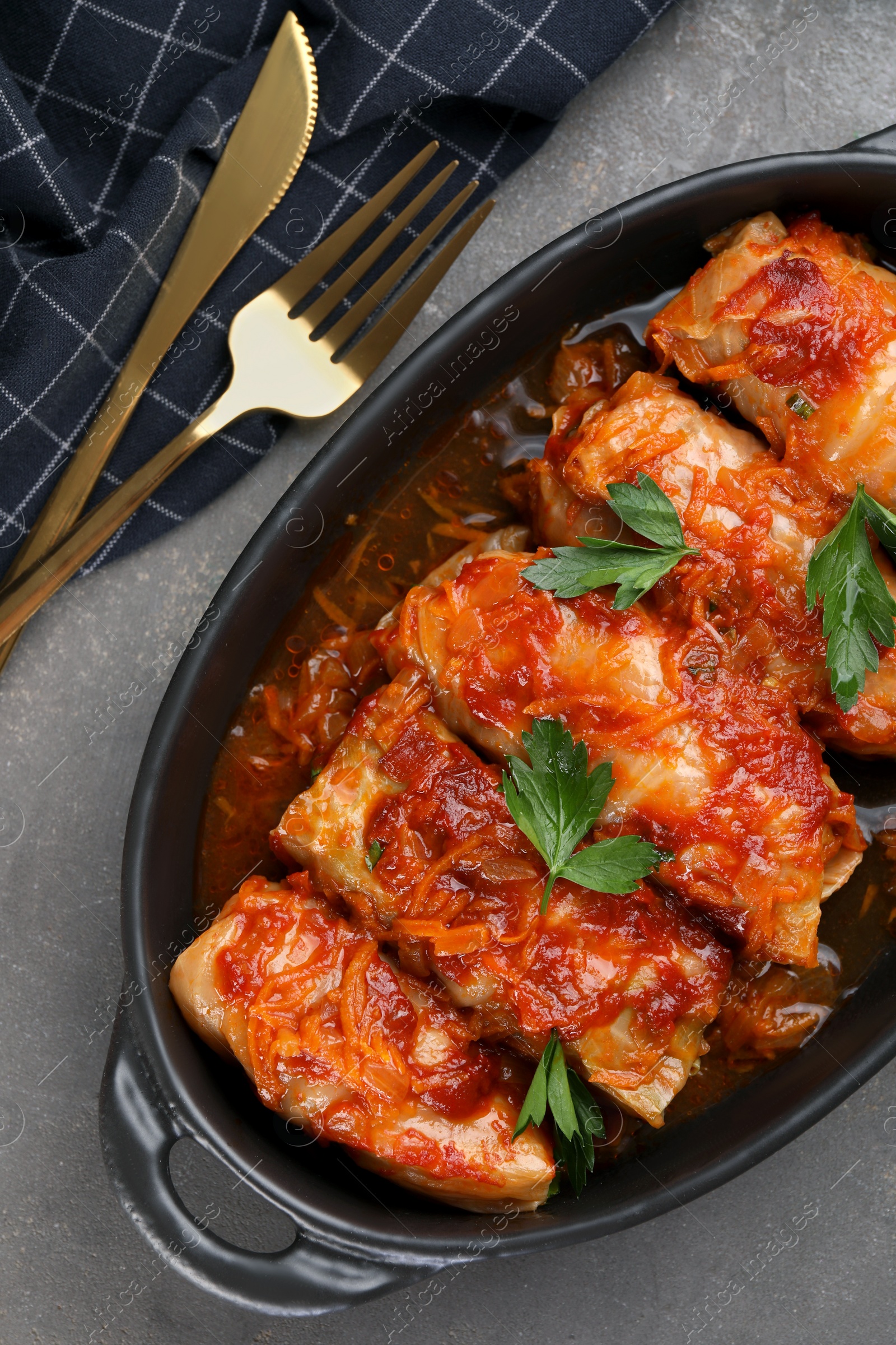 Photo of Delicious stuffed cabbage rolls cooked with tomato sauce on grey table, flat lay