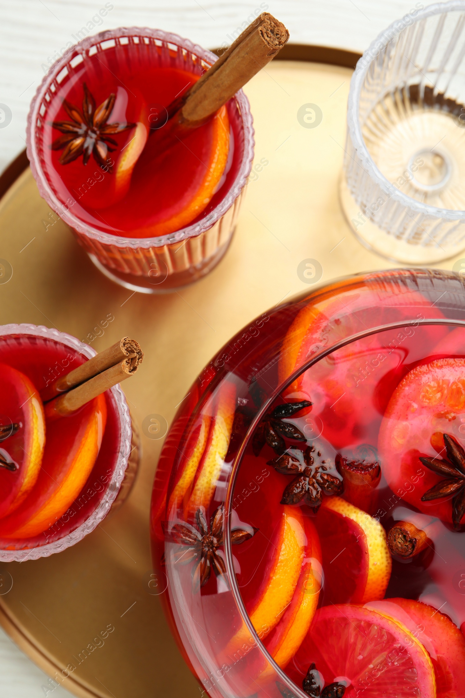 Photo of Glasses and bowl of delicious aromatic punch drink on white wooden table, top view