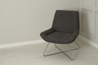 Photo of Stylish grey armchair near light wall in room. Space for text