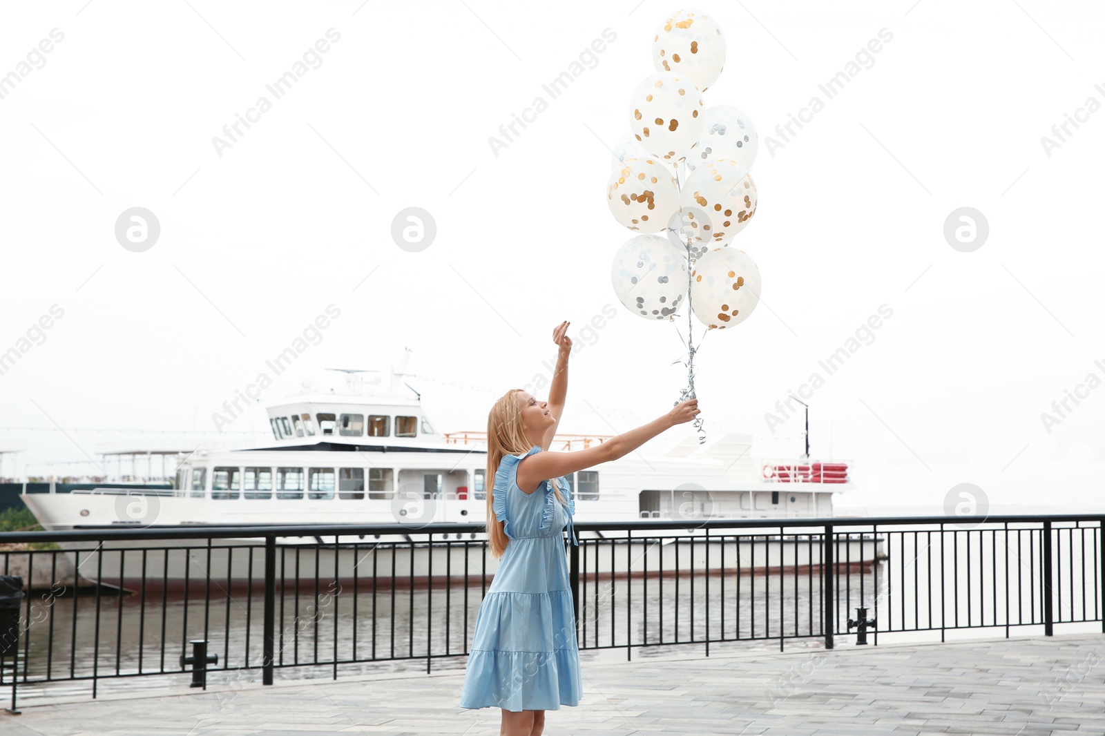 Photo of Beautiful young woman with bunch of balloons outdoors