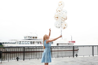 Beautiful young woman with bunch of balloons outdoors