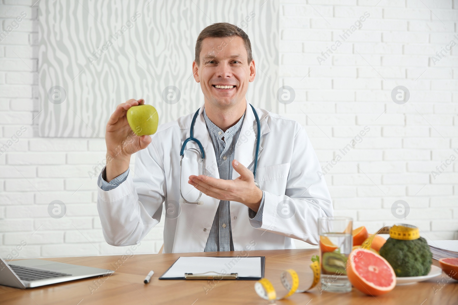 Photo of Nutritionist with apple at desk in office