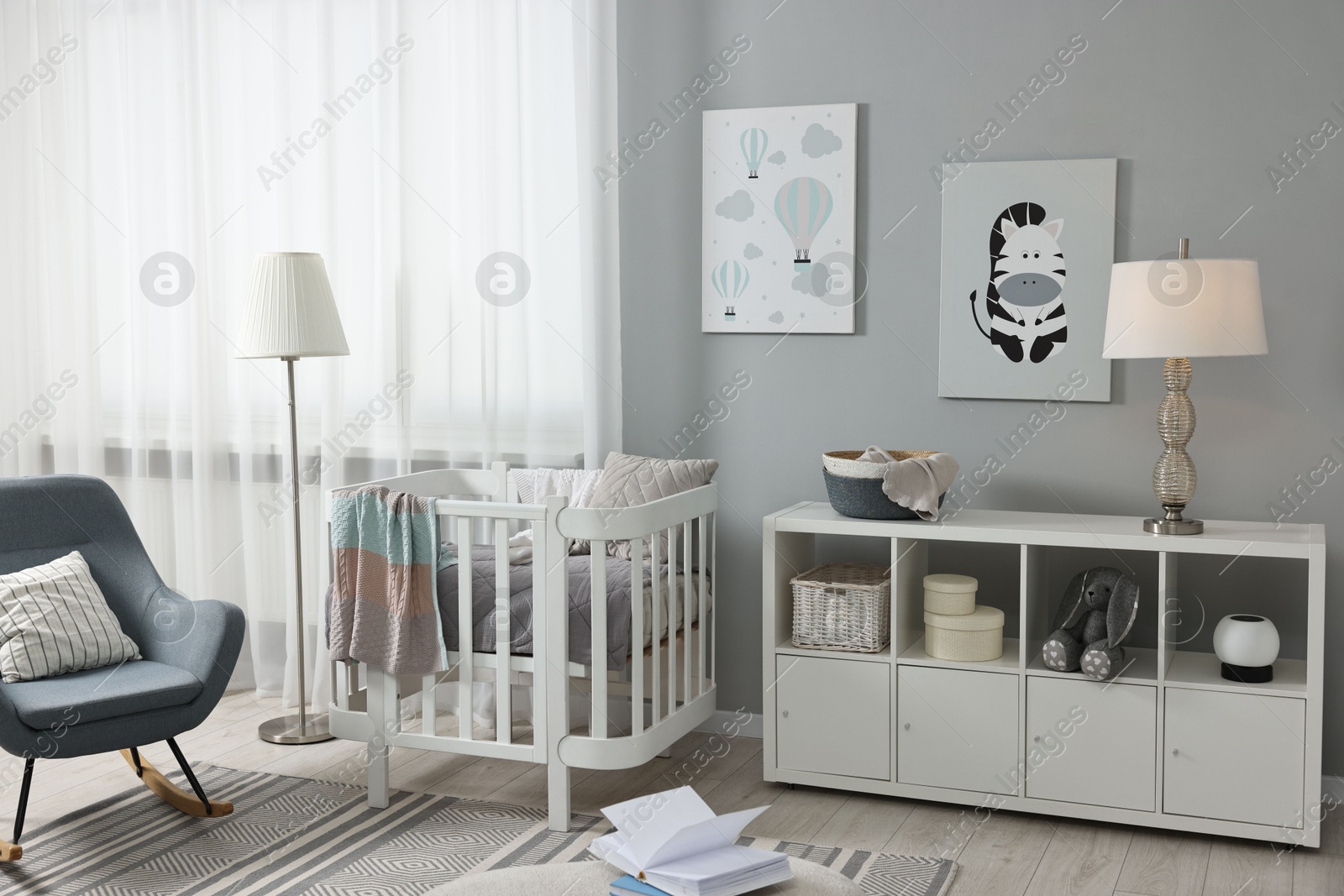 Photo of Newborn baby room interior with stylish furniture, comfortable crib and pictures of on wall