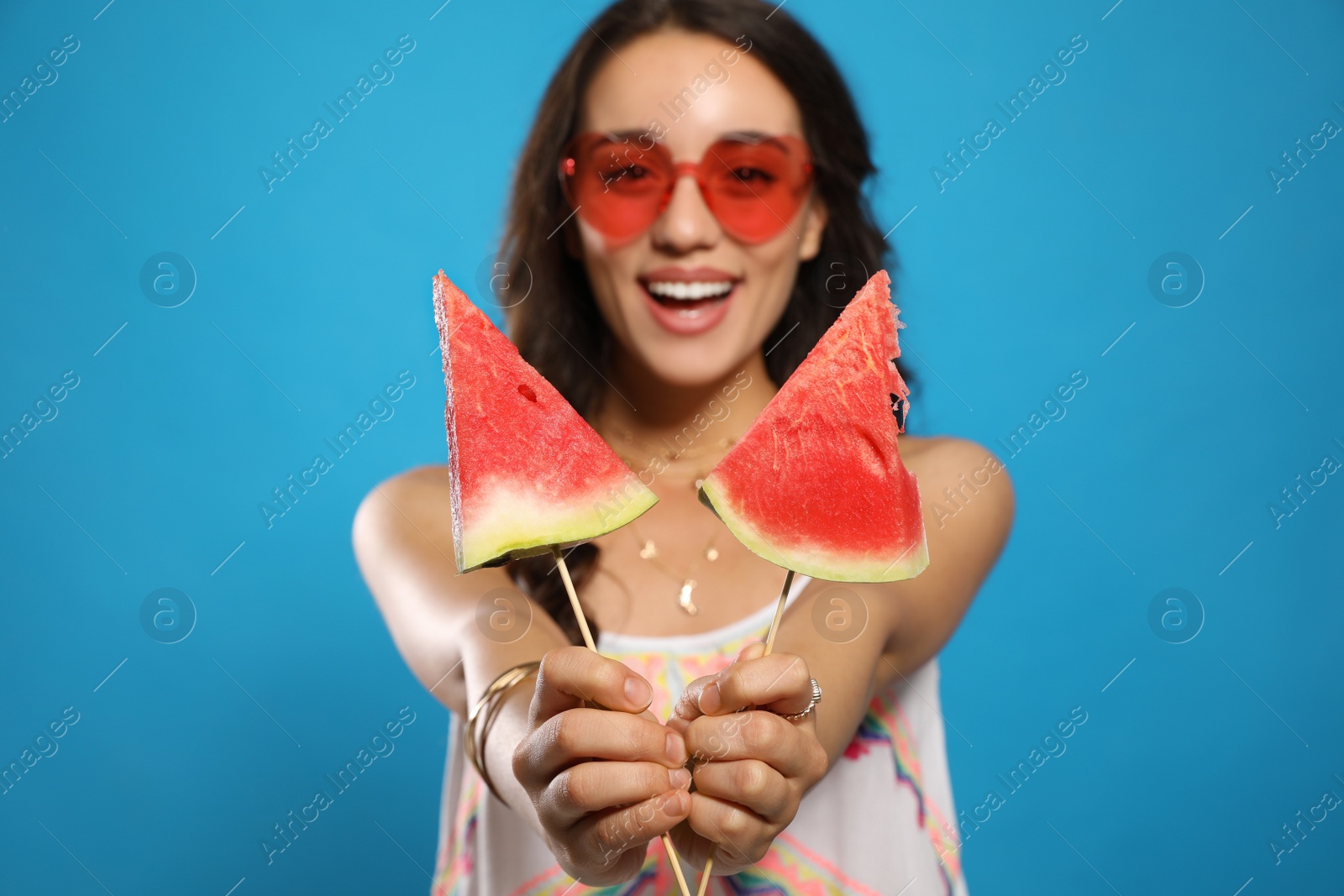 Photo of Beautiful young woman against blue background, focus on hands with watermelon
