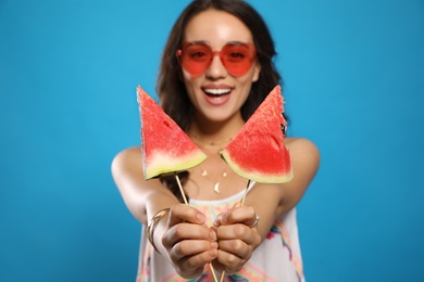 Photo of Beautiful young woman against blue background, focus on hands with watermelon