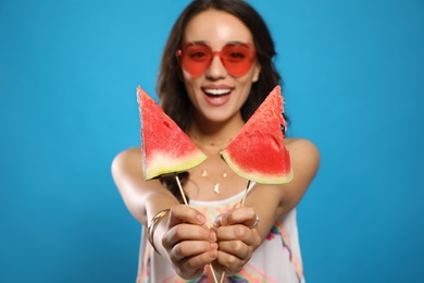 Beautiful young woman against blue background, focus on hands with watermelon