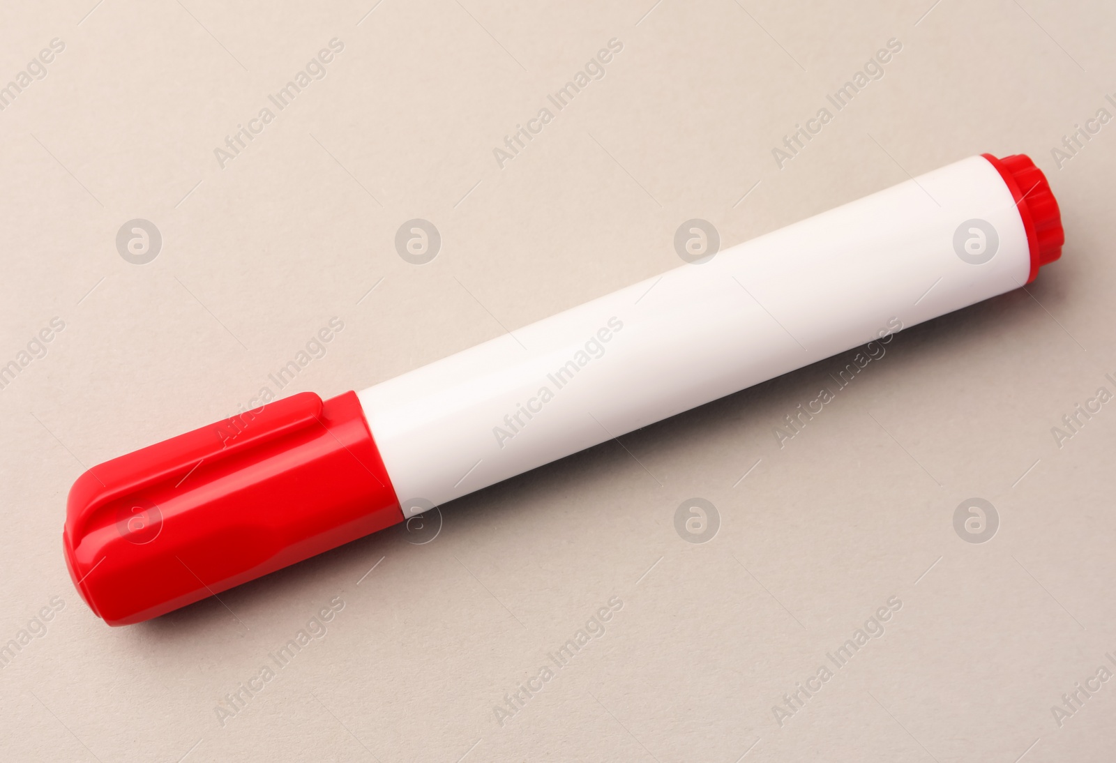 Photo of Bright red marker on beige background, closeup