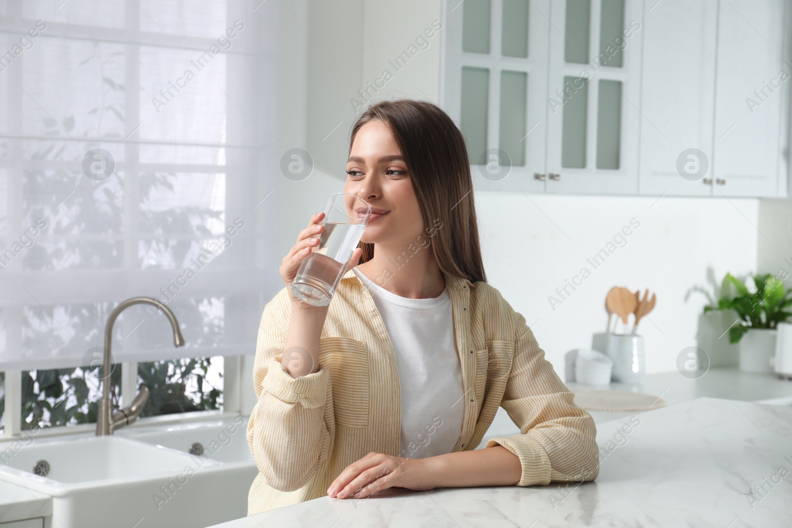 Photo of Woman drinking tap water from glass in kitchen