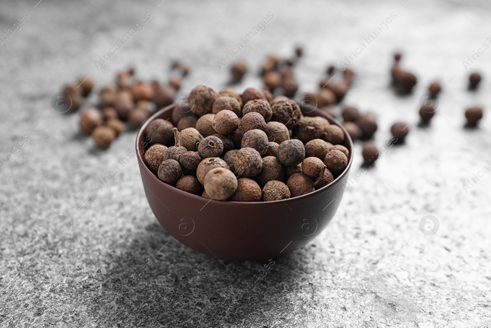 Photo of Black peppercorns in bowl on grey table