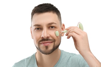 Man using nephrite facial roller on white background