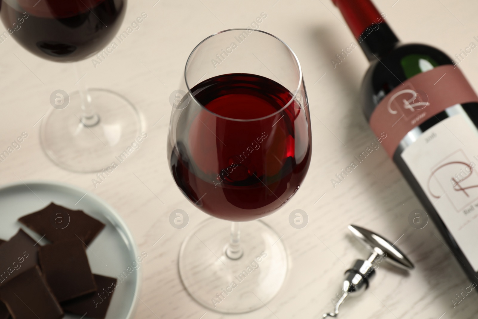 Photo of Tasty red wine and chocolate on white wooden table