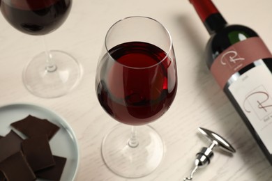 Tasty red wine and chocolate on white wooden table
