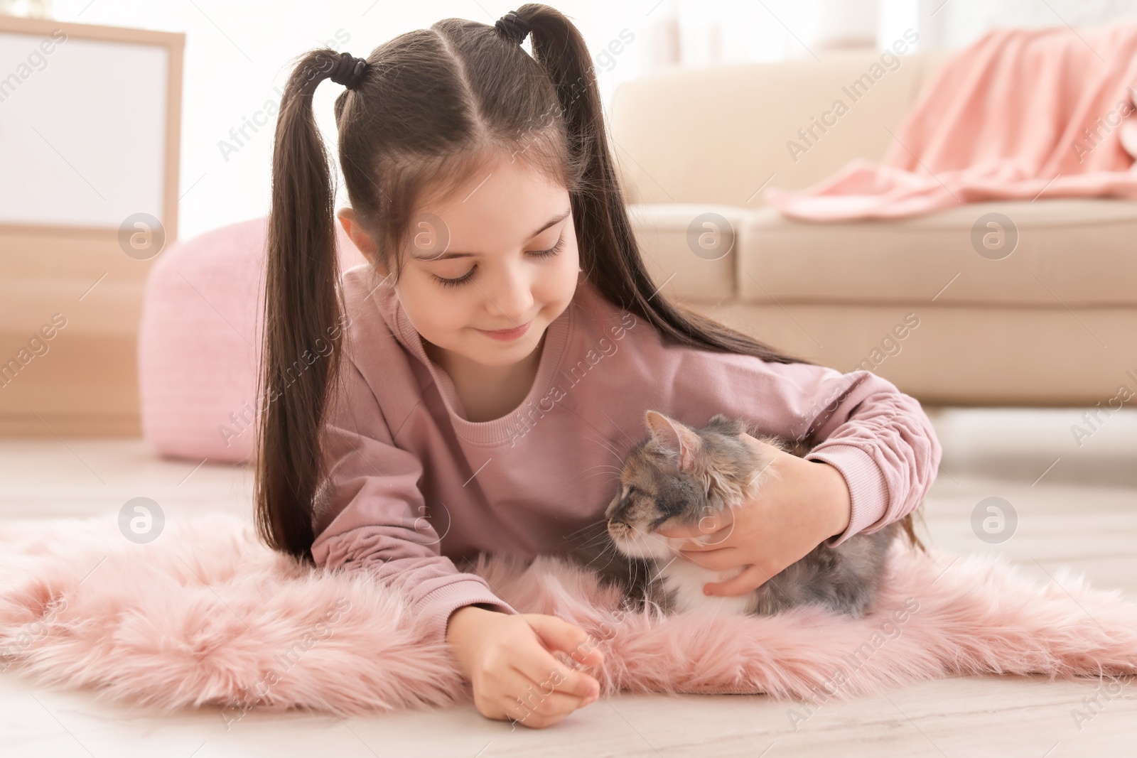 Photo of Cute little girl with cat lying on floor at home