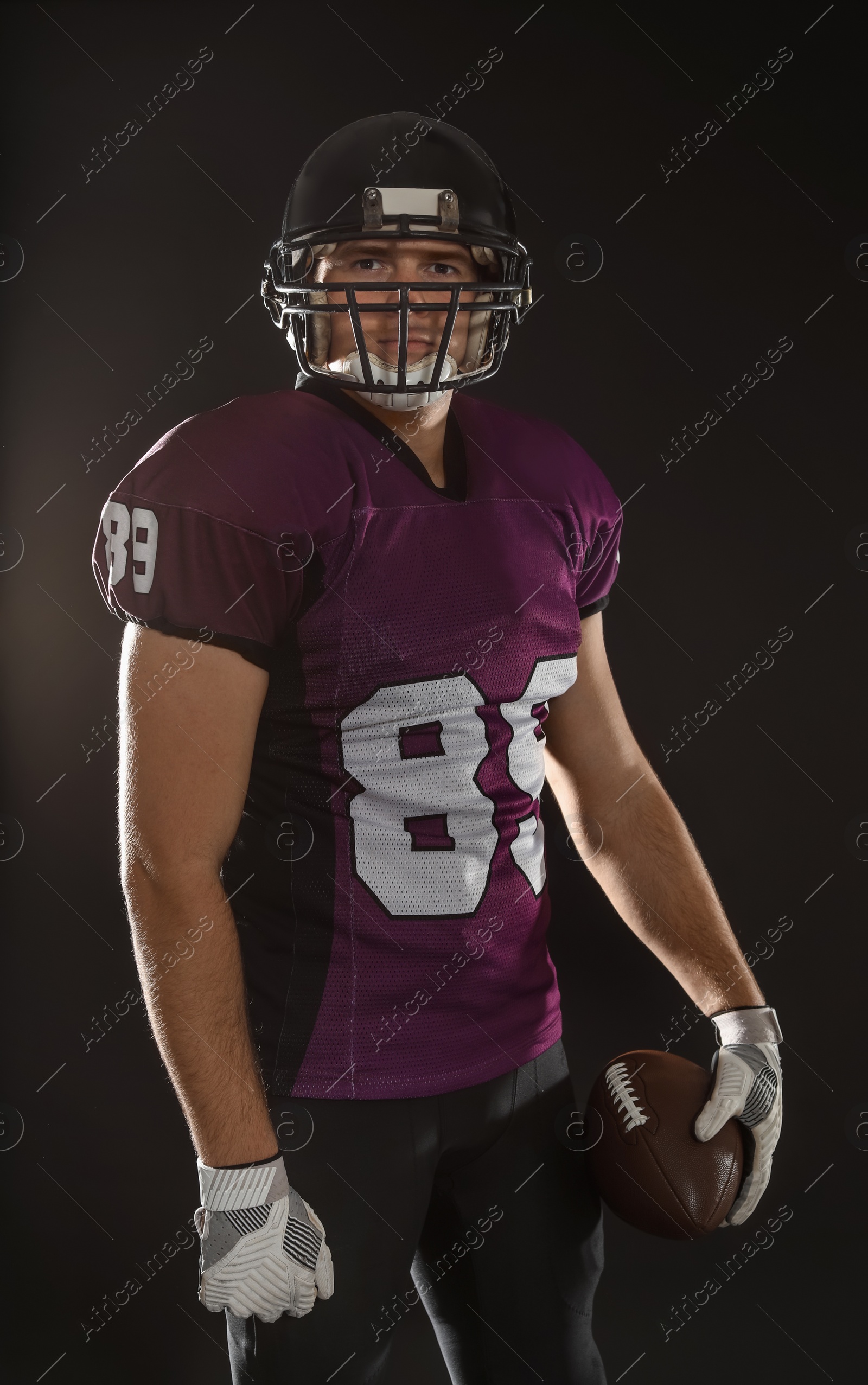 Photo of American football player with ball on dark background