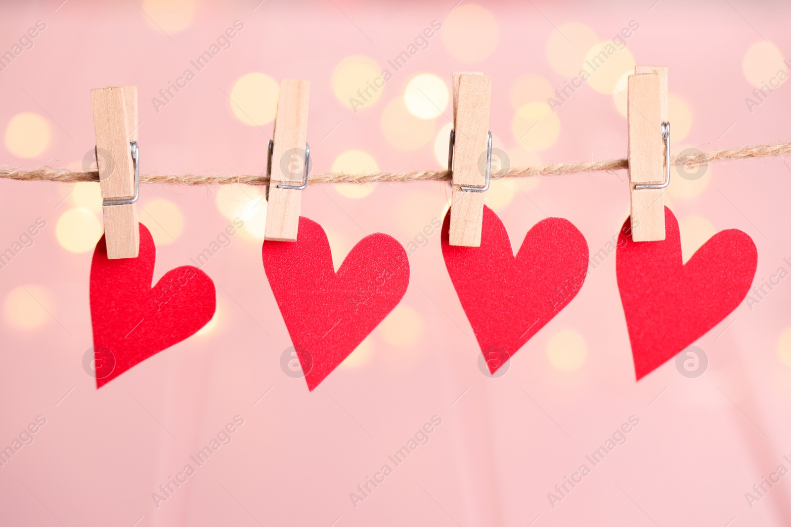 Photo of Red hearts hanging on rope against festive lights. St. Valentine's day