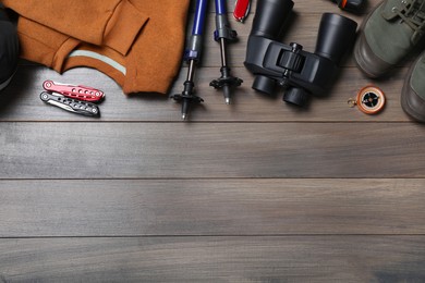 Flat lay composition with trekking poles and other hiking equipment on wooden background, space for text