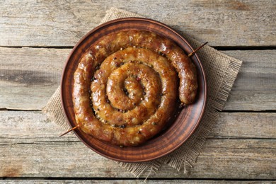 Photo of Plate with tasty homemade sausages on wooden table, top view
