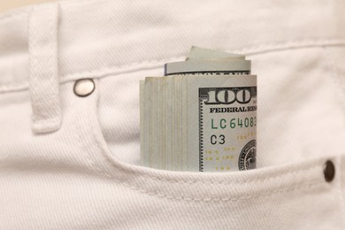 Photo of Dollar banknotes in pocket of white jeans, closeup. Spending money