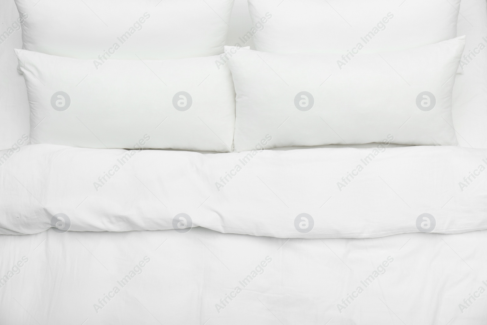 Photo of Soft white pillows and blanket on bed, top view