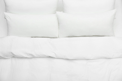 Photo of Soft white pillows and blanket on bed, top view