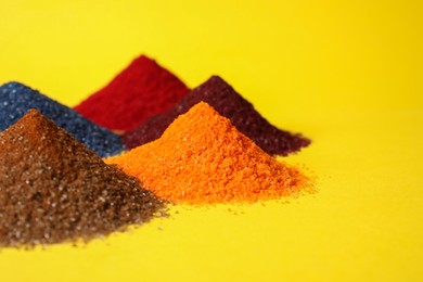 Heaps of different bright food coloring on yellow background, closeup