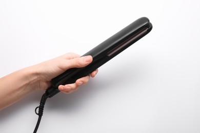 Photo of Woman holding flat hair iron on white background, closeup