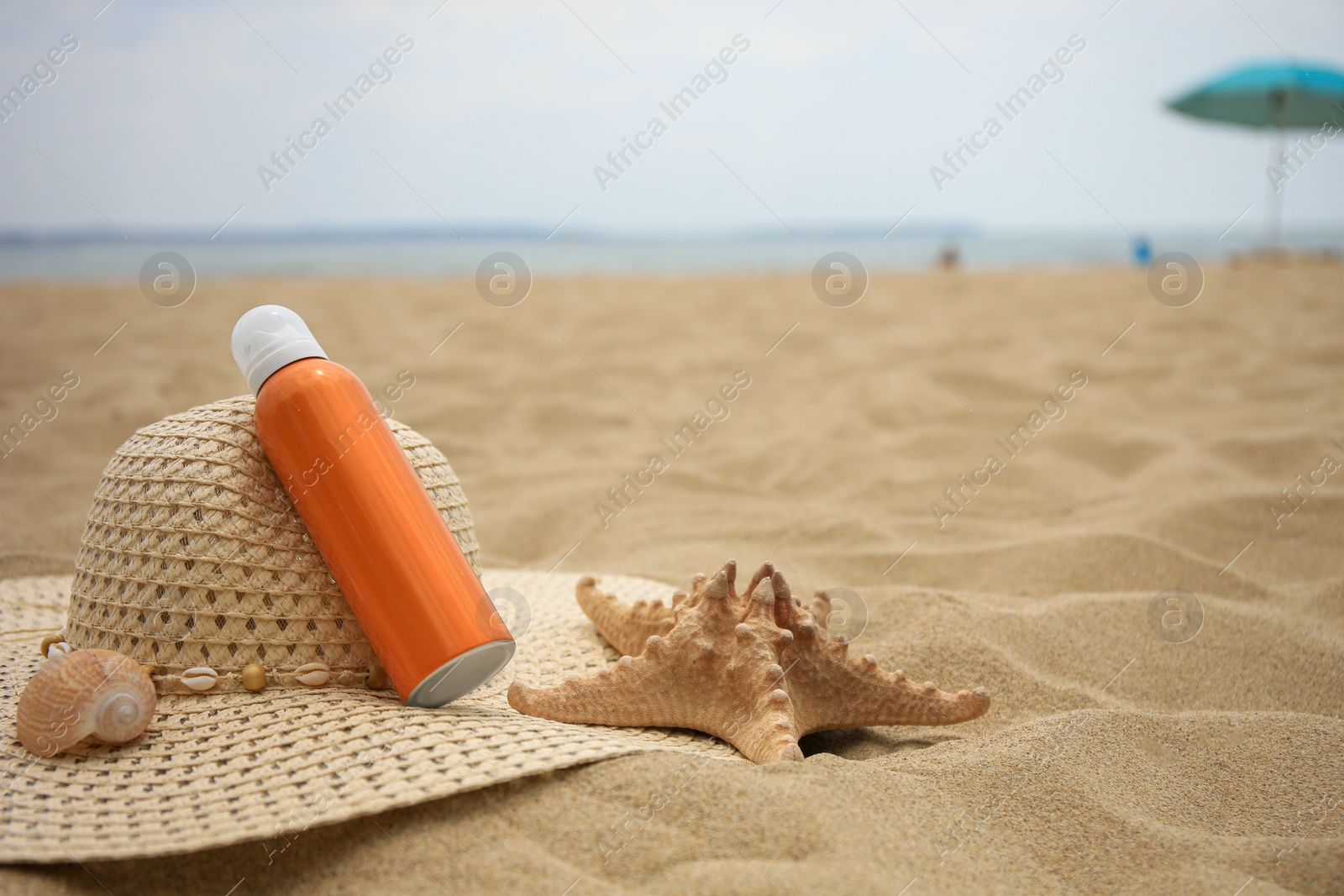 Photo of Sunscreen, hat and starfish on sand, space for text. Sun protection care