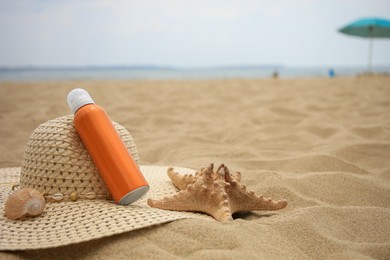 Photo of Sunscreen, hat and starfish on sand, space for text. Sun protection care