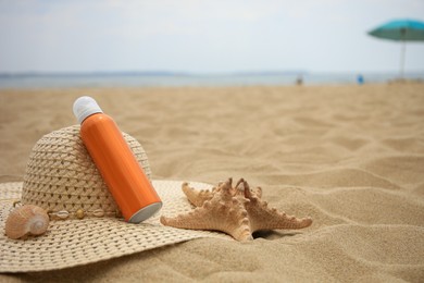 Sunscreen, hat and starfish on sand, space for text. Sun protection care