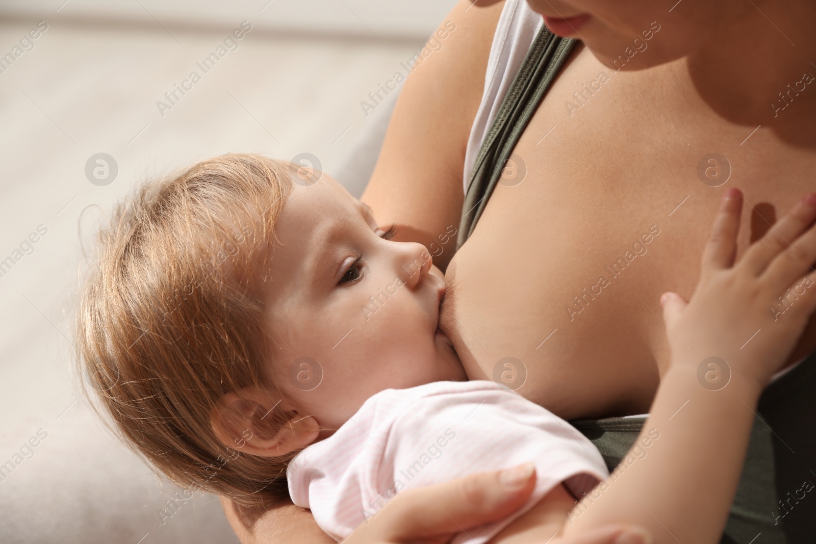 Photo of Woman breastfeeding her little baby at home, closeup