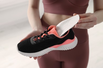 Sporty woman putting orthopedic insole into shoe on blurred background, closeup. Foot care