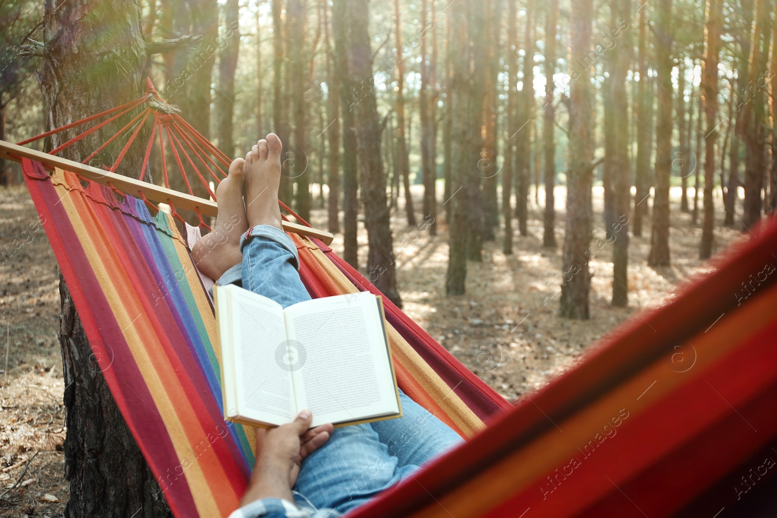 Photo of Man with book relaxing in hammock outdoors on summer day, closeup