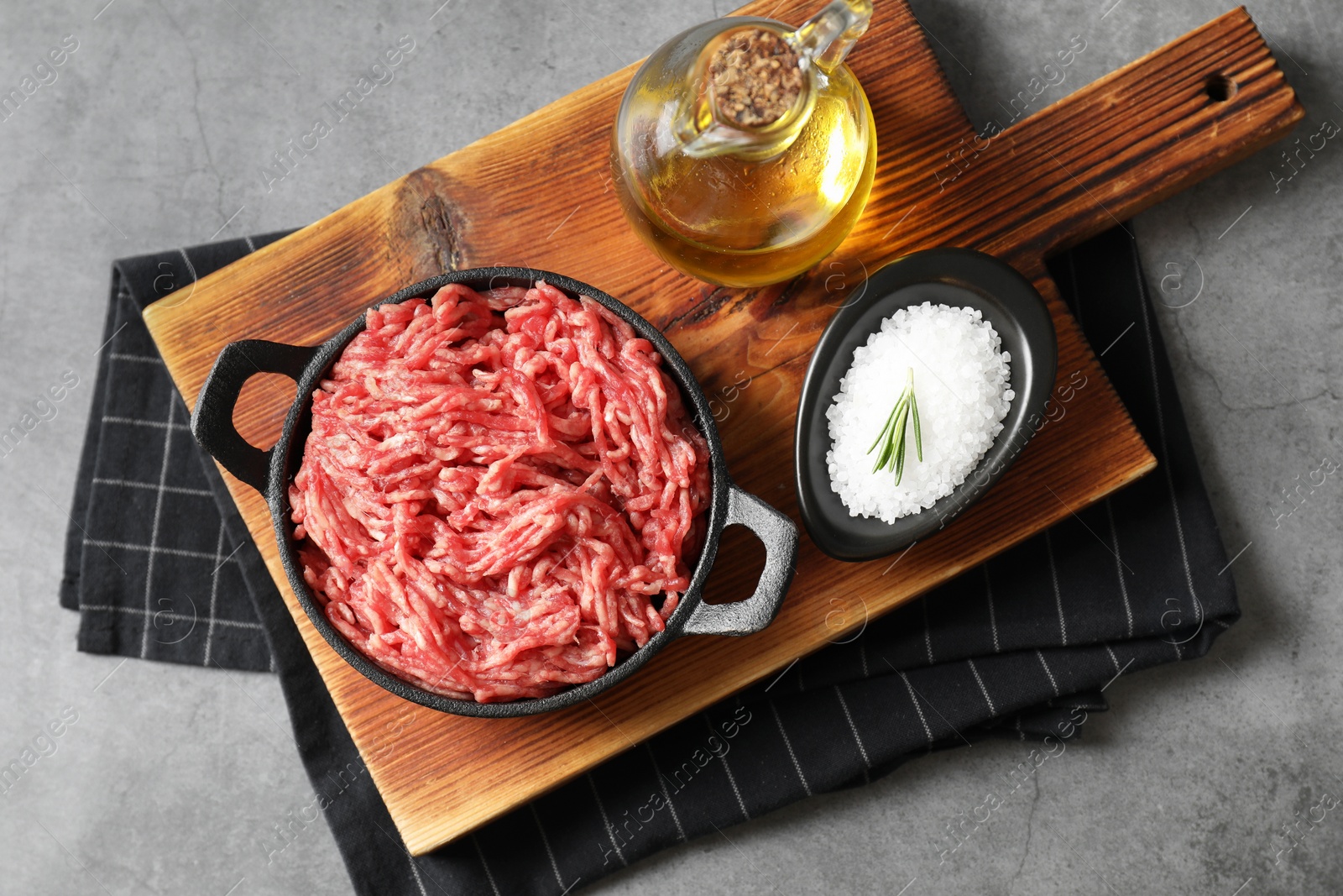 Photo of Raw ground meat in bowl, salt and oil on grey table, top view