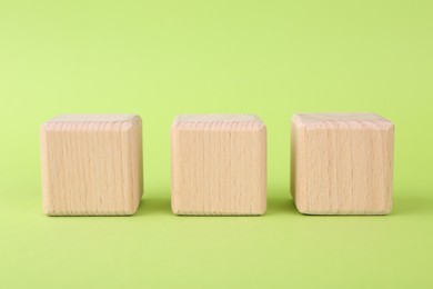 Photo of Blank wooden cubes on light green background, closeup