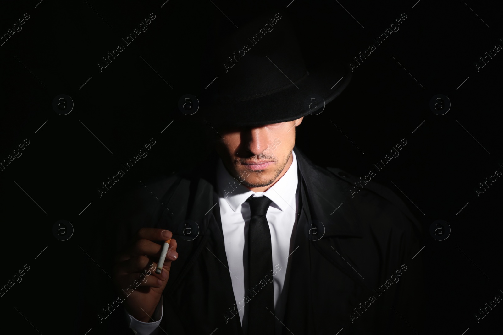 Photo of Old fashioned detective with cigarette on dark background