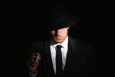 Photo of Old fashioned detective with cigarette on dark background