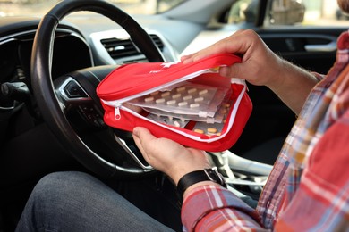 Photo of Man with first aid kit inside car, closeup