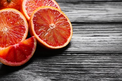 Photo of Cut fresh ripe red oranges on black wooden table, closeup. Space for text