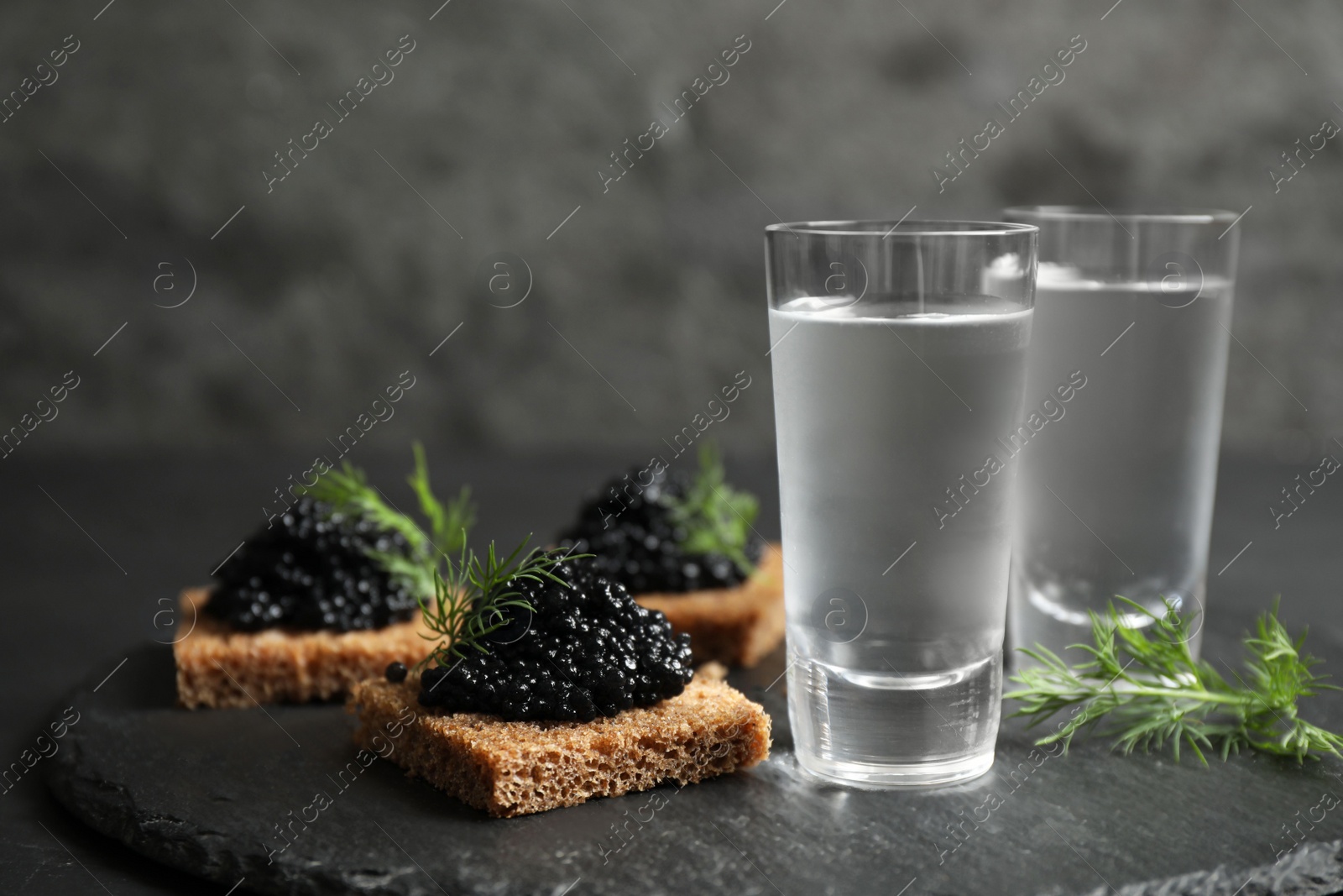 Photo of Cold Russian vodka and sandwiches with black caviar on table, closeup