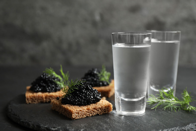 Photo of Cold Russian vodka and sandwiches with black caviar on table, closeup