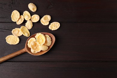 Photo of Spoon and tasty crispy corn flakes on wooden table, flat lay. Space for text