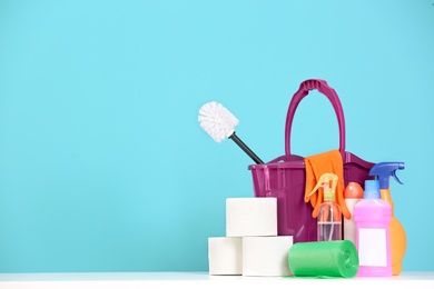 Photo of Bucket with cleaning supplies on color background