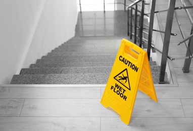 Photo of Safety sign with phrase Caution wet floor near stairs. Cleaning service