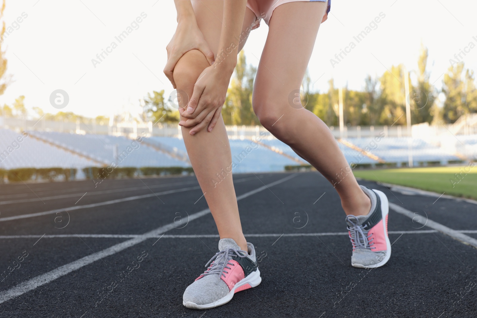 Photo of Young woman having knee problems at stadium, closeup