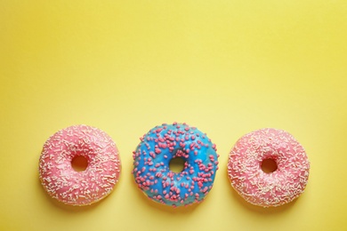 Photo of Delicious glazed doughnuts on color background, top view