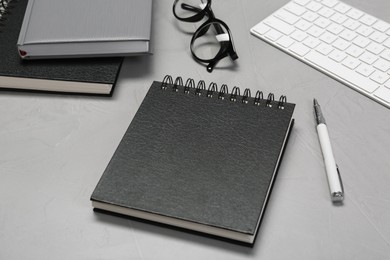 Photo of Black notebook and pen on light grey table