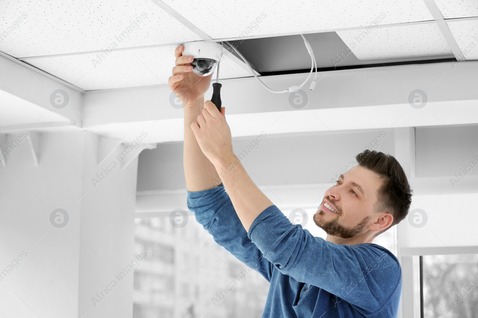 Photo of Technician installing CCTV camera on ceiling indoors