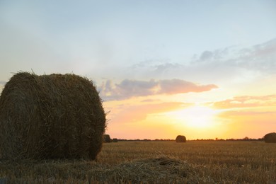 Photo of Beautiful view of agricultural field with hay bale at sunset
